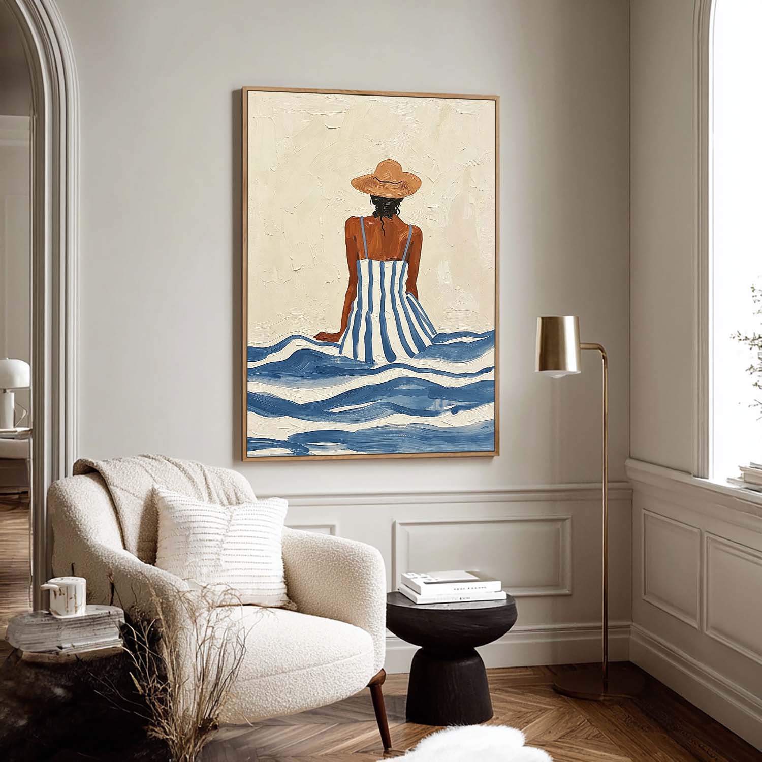 Living room with a framed artwork of a woman in a striped dress sitting in water, a beige armchair, and a lamp.